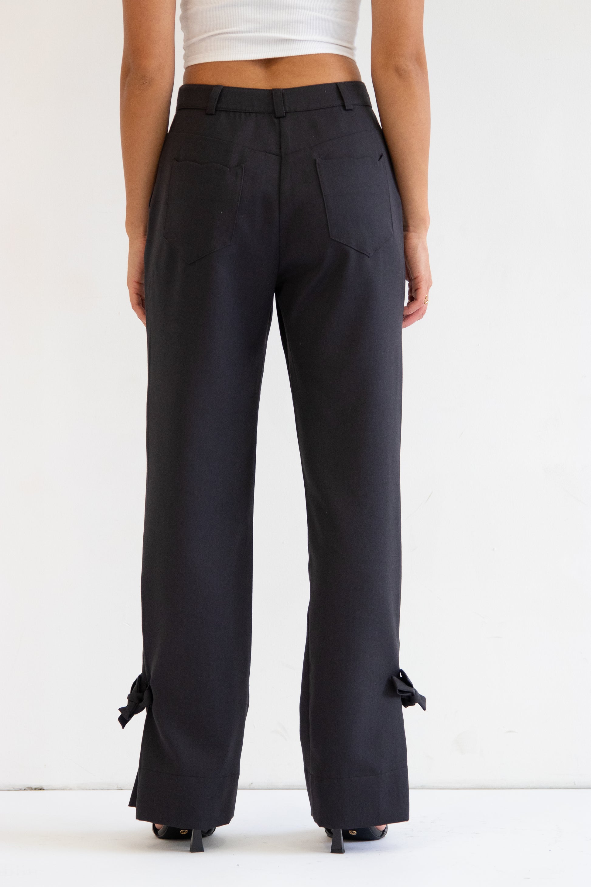 Close up back view of pants with wave detail back pockets and bows at hem